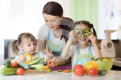 Mom teaches two daughters to cook at the kitchen table with raw food Stock Photo