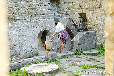 Mom with toddler observing broken iron mill gear in Dolsky mill Stock Photo