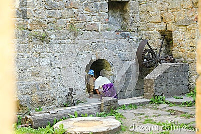 Mom with toddler observing broken iron mill gear in Dolsky mill Stock Photo