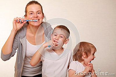 Mom and two blond boys brush their teeth Stock Photo