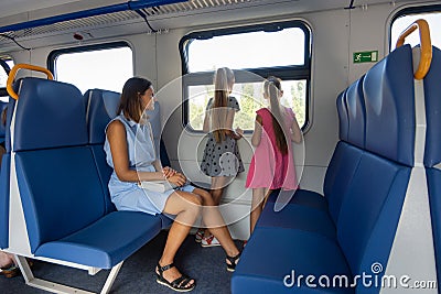 Mom and two daughters ride in an electric train, a general view of the seats Stock Photo