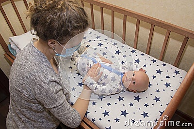 Mom, who is ill, keeps her baby in a protective medical mask Stock Photo