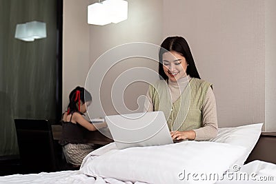 Mom working online at home sharing vacations with little daughter. Funny lifestyle family moment Stock Photo