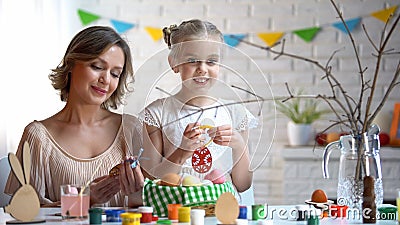 Mommy and daughter decorating branches with hand-made toys, Easter traditions Stock Photo