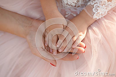 Moms hand holds in her palm the hands of her little daughter Stock Photo