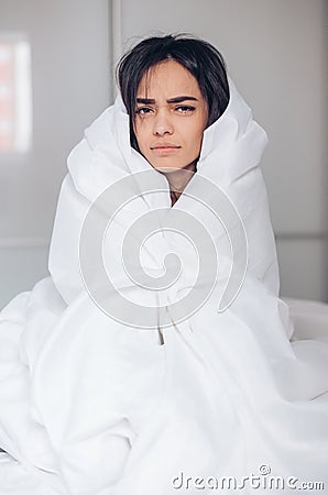 Monday morning. Beautiful young dissatisfied woman wrapped in blanket sitting on bed Stock Photo