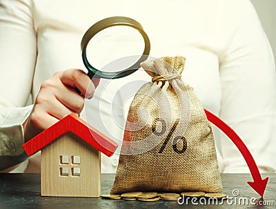 Money bag with percents, down arrow and miniature house. The concept of low interest rates on mortgage loans or rentals. The Stock Photo