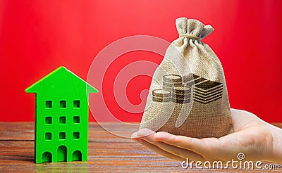 Money bag and wooden house. Real estate concept. Business and finance. Savings on the purchase of housing and apartments. Mortgage Stock Photo