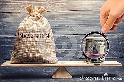 Money bag with the word Investments and dollars on scales. Attraction of financial resources for investment projects. Risk Stock Photo