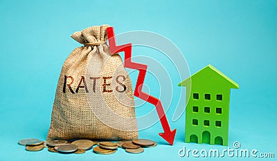 Money bag with the word Rates, down arrow and wooden house. The concept of reducing interest rates on mortgages. Low rental rate Stock Photo