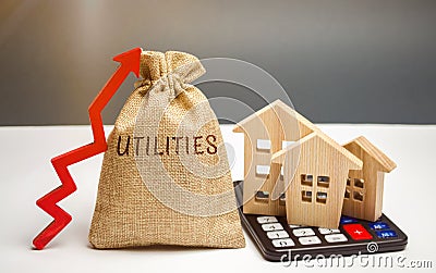 Money bag with the word Utilities and an up arrow and houses on a calculator. The concept of raising prices for the use of Stock Photo