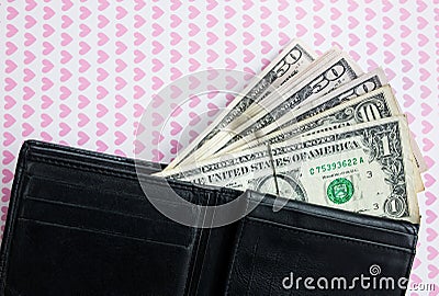 Money in the black leather wallet is lying on the background with pink hearts. Loving dollars. Time to go shopping and buy things Stock Photo