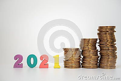 2021 Money, Business and planning Concept. Colorful wooden number letter with unstable stack of gold coins on white background Stock Photo