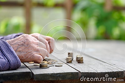 Money, coins, the grandmother on pension and the concept of life, minimum - wrinkled hands of the old woman touch coins on a woode Stock Photo