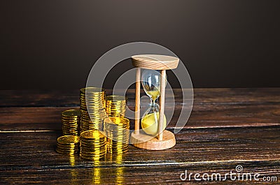 Money coins and an sand hourglass. Fair hourly wages. Time is money. Deposit. Profitability and return on investment. Balance Stock Photo