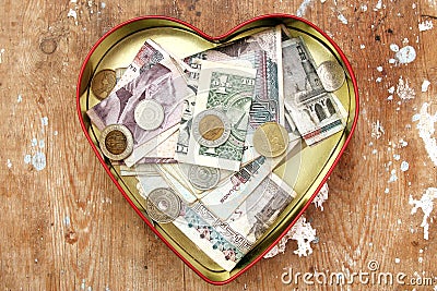 Money donation and saving in heart box Stock Photo