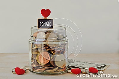 Money jar full of coins with Donate label and hearts - Charity concept Stock Photo