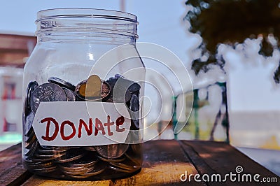 money jar with a label with the word donations on it and wooden,outside photo on donate written jar Stock Photo