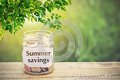 Money in the jar on wooden table and text Summer Savings Stock Photo