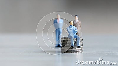 The man sitting on the coin and two men standing behind it. Stock Photo