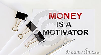 MONEY IS A MOTIVATOR written on a white page with office tools Stock Photo