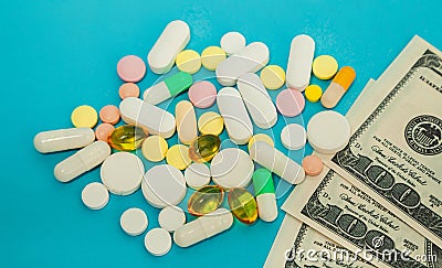 Money pills. Medicine pills on dollar bills on a blue background Covid-19 coronavirus pills are in one hundred dollar Stock Photo