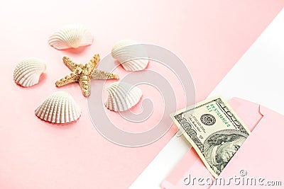 Money in a pink envelope, starfish, seashells on a blue background. Travel budget. Copy space, top view. Stock Photo