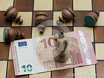 Money Rules Concept: King Chess Piece On 10 Euro Banknote With Defeated Pawns Stock Photo