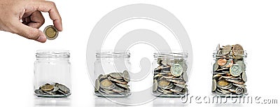 Money saving, Hand putting coin in glass jar with coins inside growing up, on white background Stock Photo