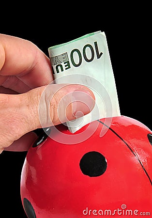 Puting money in a pig Stock Photo