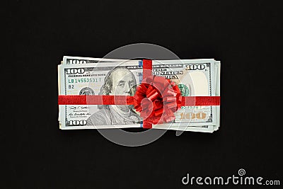 Money us dollars cash gift with red ribbon on black background. American Dollar 100 banknote gift profit concept Stock Photo