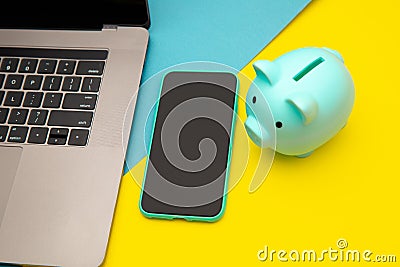 Moneybox near laptop and smartphone, place for text. Finance and budget concept. Piggy bank in pink color with gadgets Stock Photo