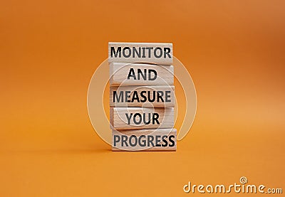 Monitor and Measure your Progress symbol. Wooden blocks with words Monitor and Measure your Progress. Beautiful orange background Stock Photo
