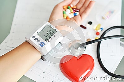 Monitoring of blood pressure of hypertensive patient, with red heart, stethoscope and pills on electrocardiogram Stock Photo