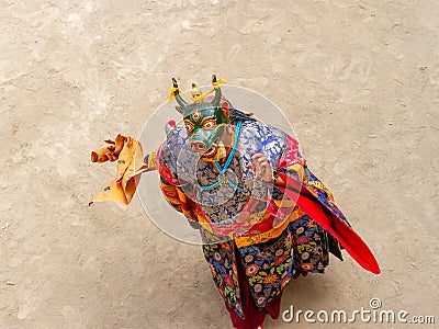 Monk in a bull deity mask with ritual dagger phurpa performs a religious masked and costumed Cham dance of Tibetan Buddhism Stock Photo