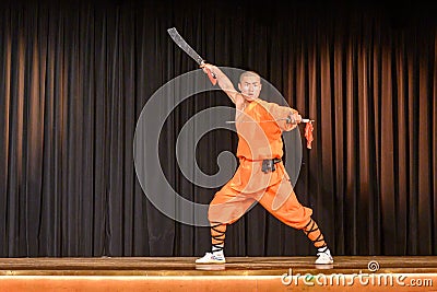 Monk at magical power show with two swords - Shaolin Kung Fu Show Editorial Stock Photo