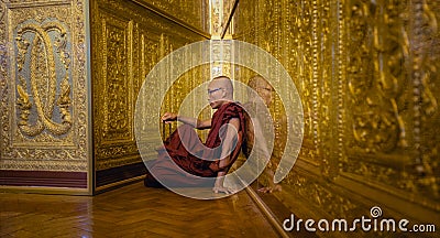 Monk in red robes prays in gold temple Editorial Stock Photo