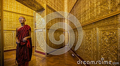 Monk in red robes prays inside temple Editorial Stock Photo