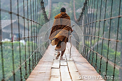 A monk with a walking stick Walk on a wooden suspension bridge in a small village in Mae Hong Son Stock Photo