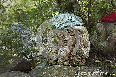 Monkey - symbol of japanese horoscope. Jizo stone statue wearing knitted and cloth hats. Stock Photo
