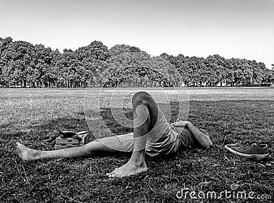 Young male skater resting on the grass with his eyes closed Editorial Stock Photo