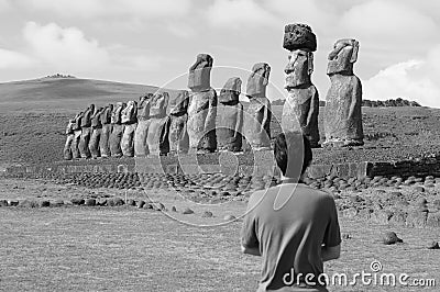 Monochrome image of massive Moai statues of Ahu Tongariki ceremonial platform with visitor in foreground, Easter island, Chile Stock Photo