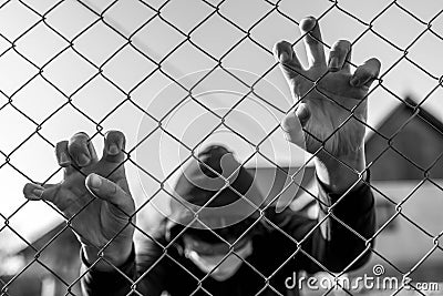 Monochrome image of a teenage boy wearing surgical mask holding wired garden fence in isolation Stock Photo