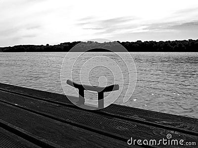 Monochrome perspective of wooden deck along a river shore with steel clit Stock Photo
