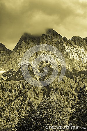 Monochrome sepia vintage style cloudy mountain landscape with trees, mist and clouds Stock Photo