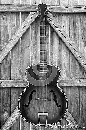Monochrome Vintage Acoustic Guitar On Fence Stock Photo