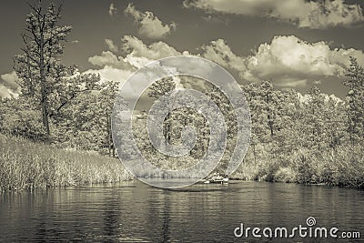 Monochromic shot of a kayak in a river flowing between thickets Stock Photo