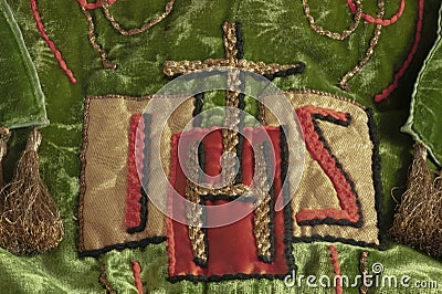 Monogram or symbol for Jesus with a gold cross at top embroidered on Christian vestment. Stock Photo