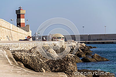 Man fishing in front of lighthouse in Monopoli, Italy Editorial Stock Photo