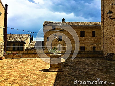 Montecassiano town, Marche region, Italy. Medieval buildings, precious ancient square and well, light and shadow, history and time Stock Photo